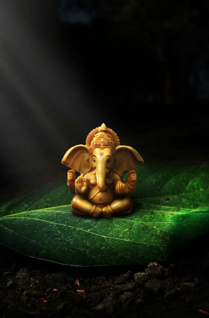 A small Ganesha figurine resting on a green leaf