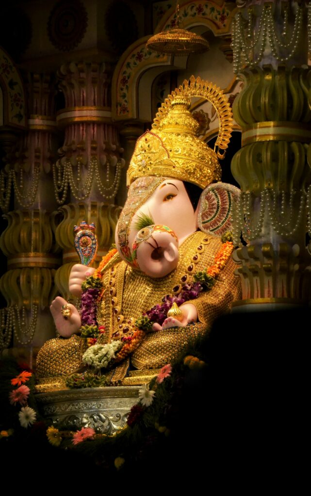 Golden Ganesha idol adorned with flowers in a temple