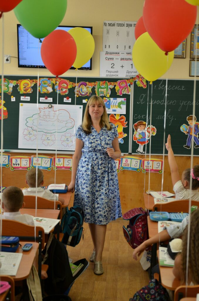 A smiling teacher in a classroom decorated with balloons