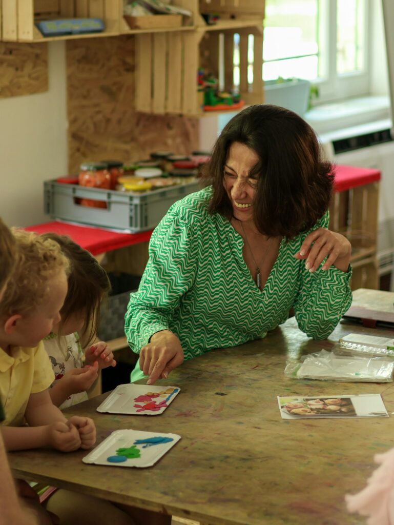 A teacher guiding two children shaping clay