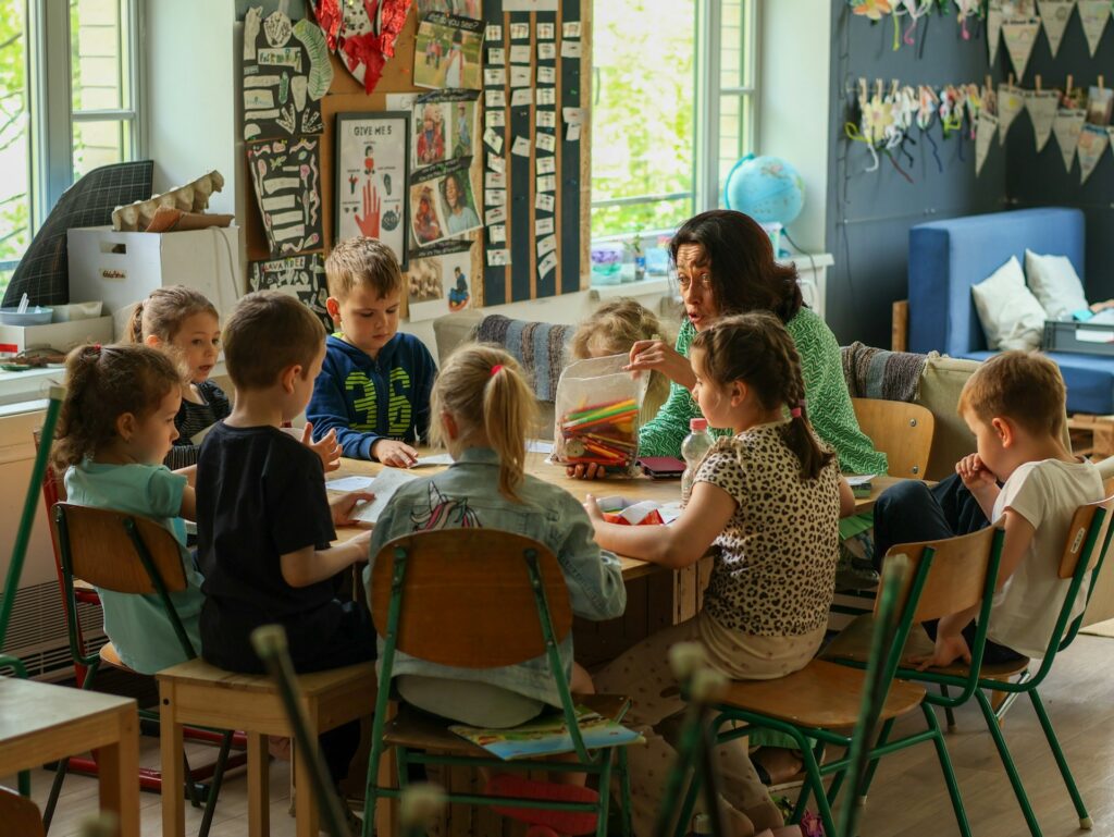 A teacher and children working together at a classroom table